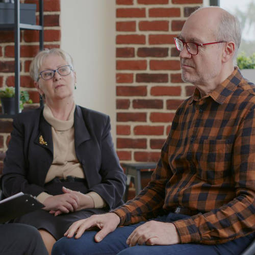 Senior person having discussion with woman about alcohol addiction at aa meeting